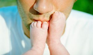A father kisses his baby's feet